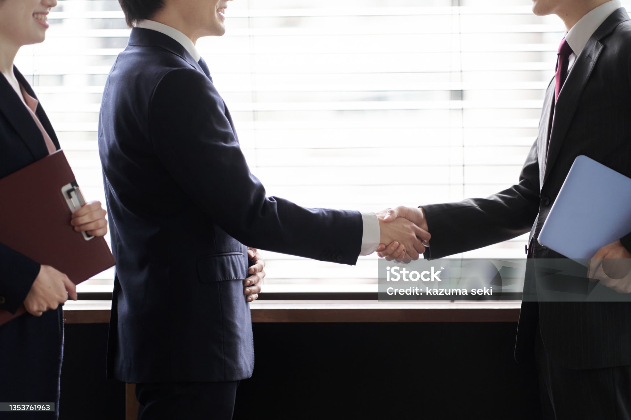 スーツを着た人同士が握手をしている画像